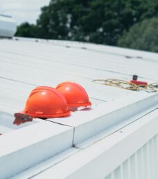 Red hard hats and safety equipment on a metal roof, emphasizing construction safety.