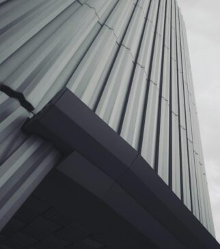 Low angle shot of a modern building with gray tones and overcast sky, emphasizing architectural lines.